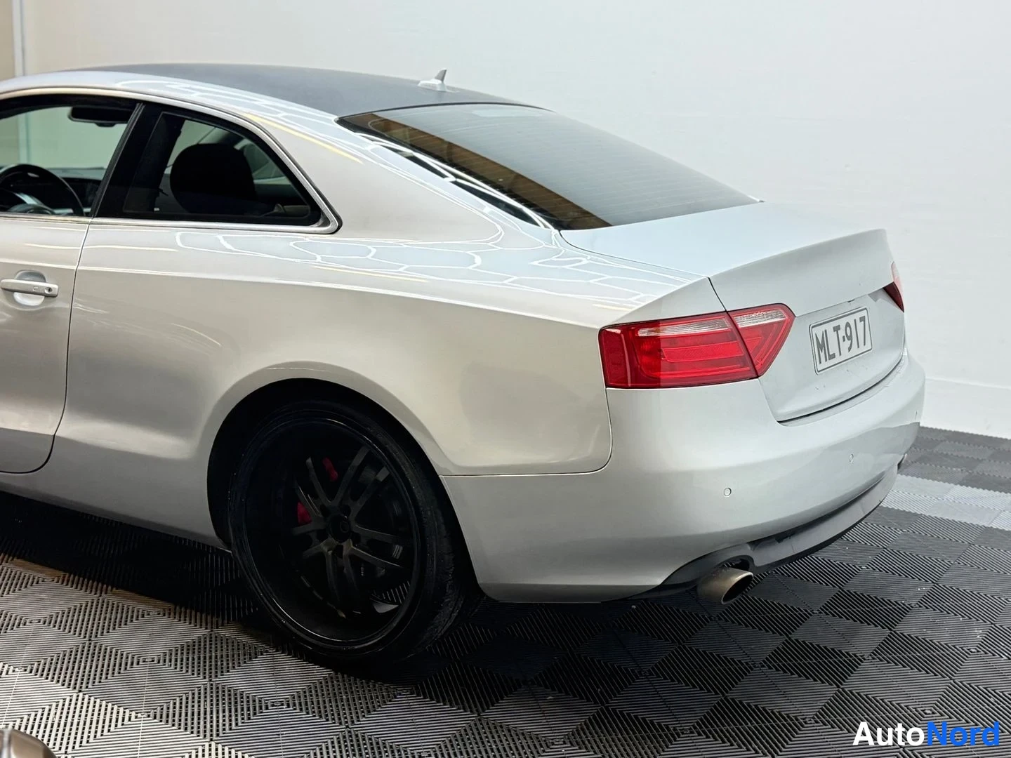 Takaviisto: Lähikuva Audi A5 -coupén takaviistosta: hopea kori, punainen takavalo, rekisterikilpi, musta vanti ja pakoputki.
