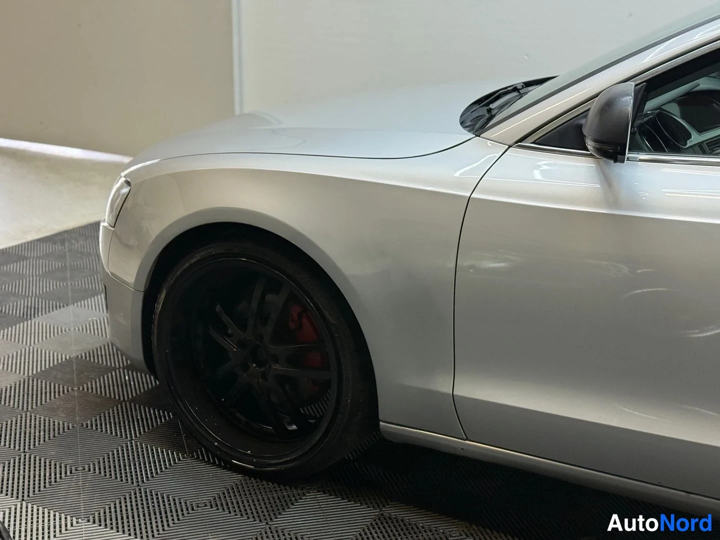 Sivulta: Lähikuva Audi A5 -coupén etusivestä ja mustasta etupyörästä, josta näkyy punainen jarrusatula.