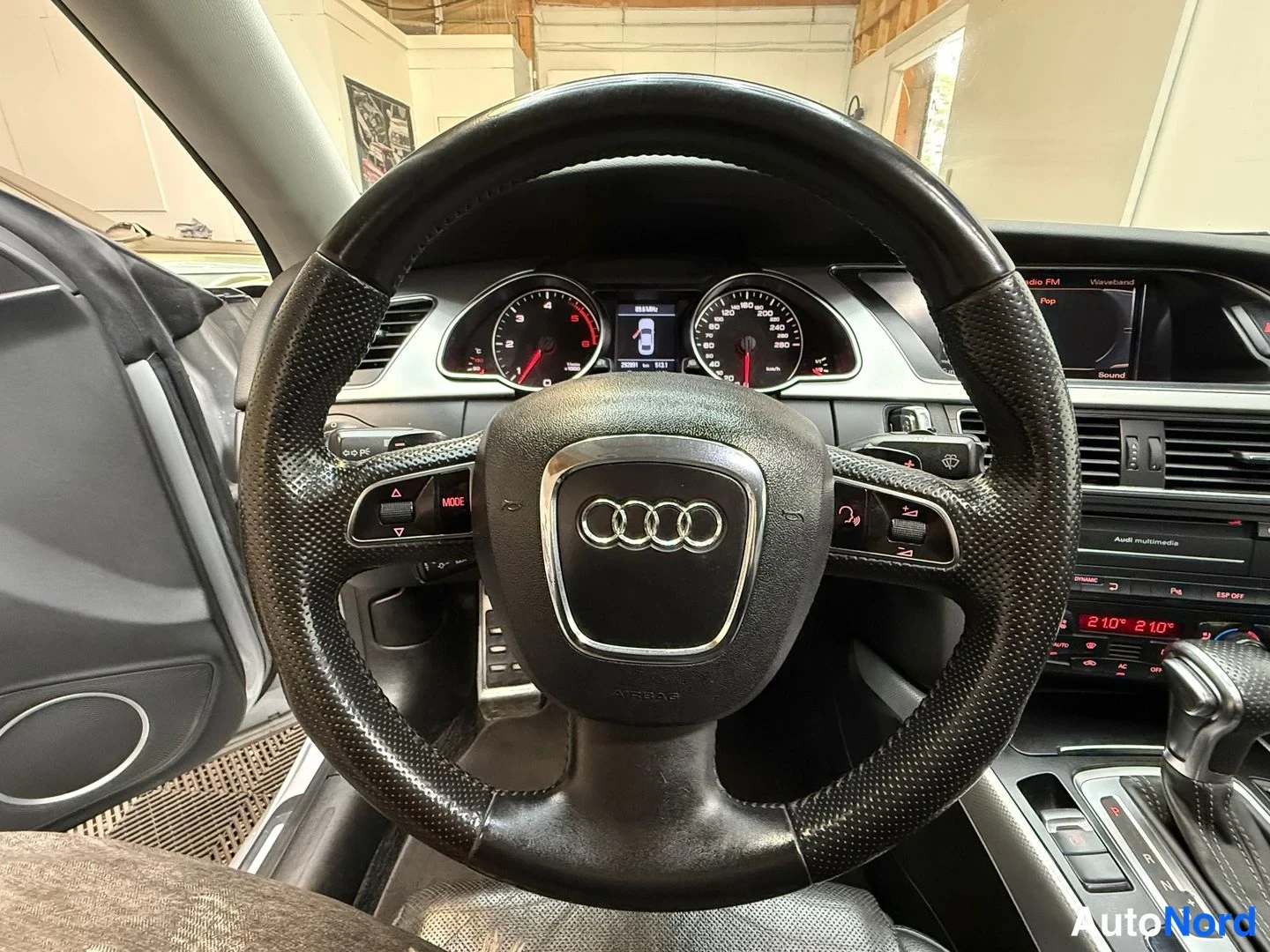Muu: Ohjauspyörän ja kojelaudan näkymä: Audi-merkkiohjauspyörä, Instrumentit ja keskikonsolin näyttö.