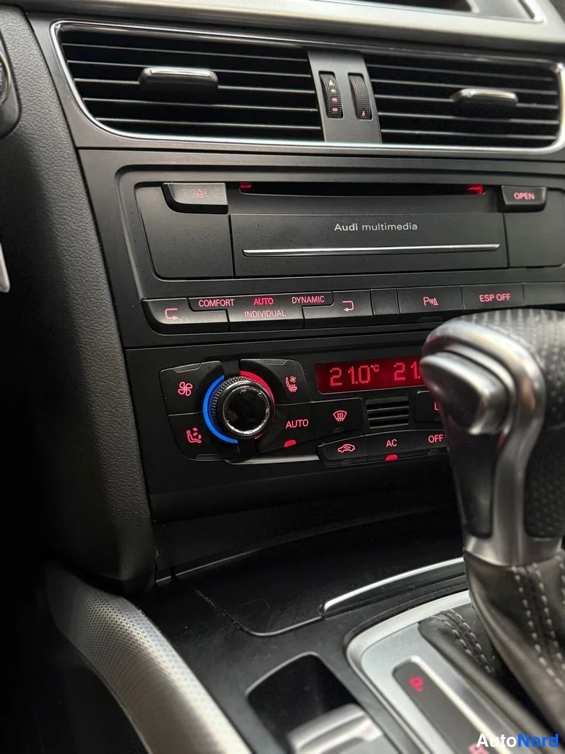 Muu: Keskikonsolin lähikuva: Audi multimedia -yksikkö, ajotilanpainikkeet ja kaksialueilmastointipaneeli.
