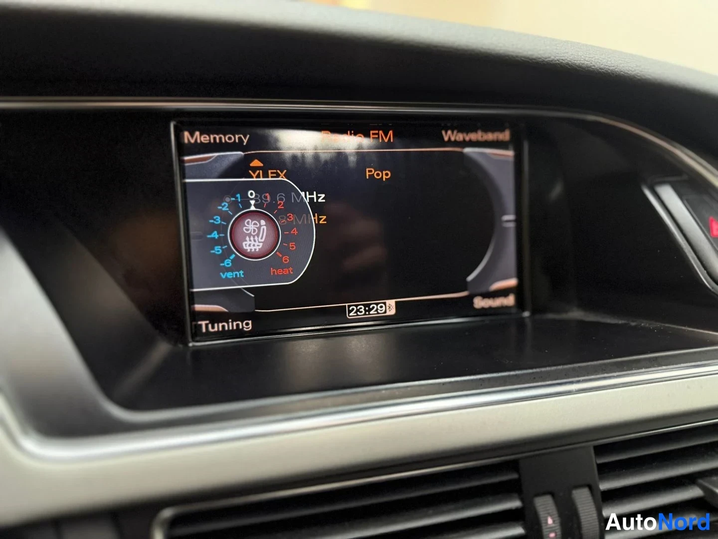 Yksityiskohta: Keskikonsolin näyttö näyttää FM-radiota (YLEX, Pop, 89,6 MHz) ja istuimenlämmityksen säätöä kellon ollessa 23:29.