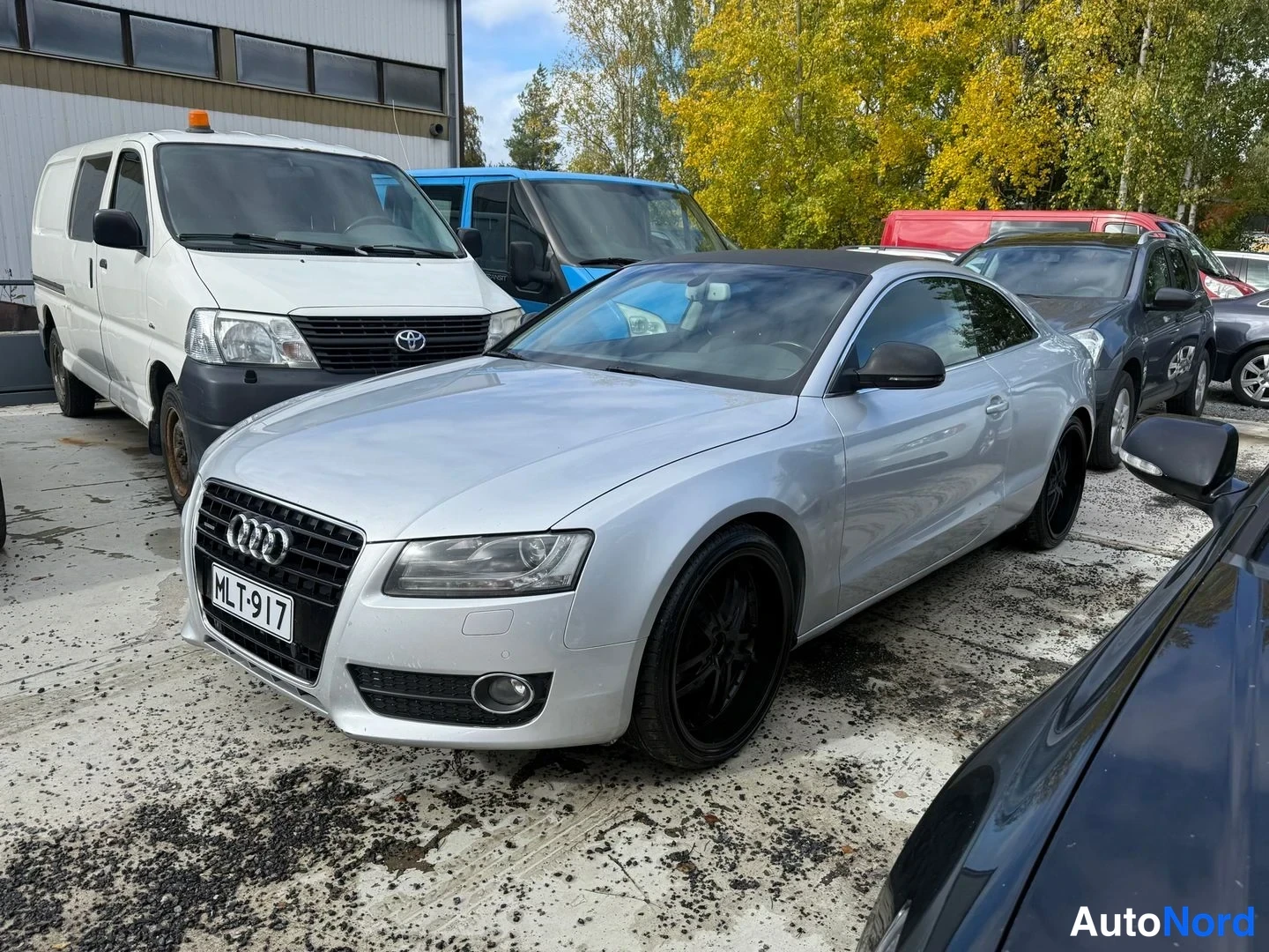 Etuviisto, nokka vasemmalle: Audi A5 - coupé edestä oikealta kuvattuna, vaalean hopeinen, rekisteritunnus, mustat kevytmetallivanteet.