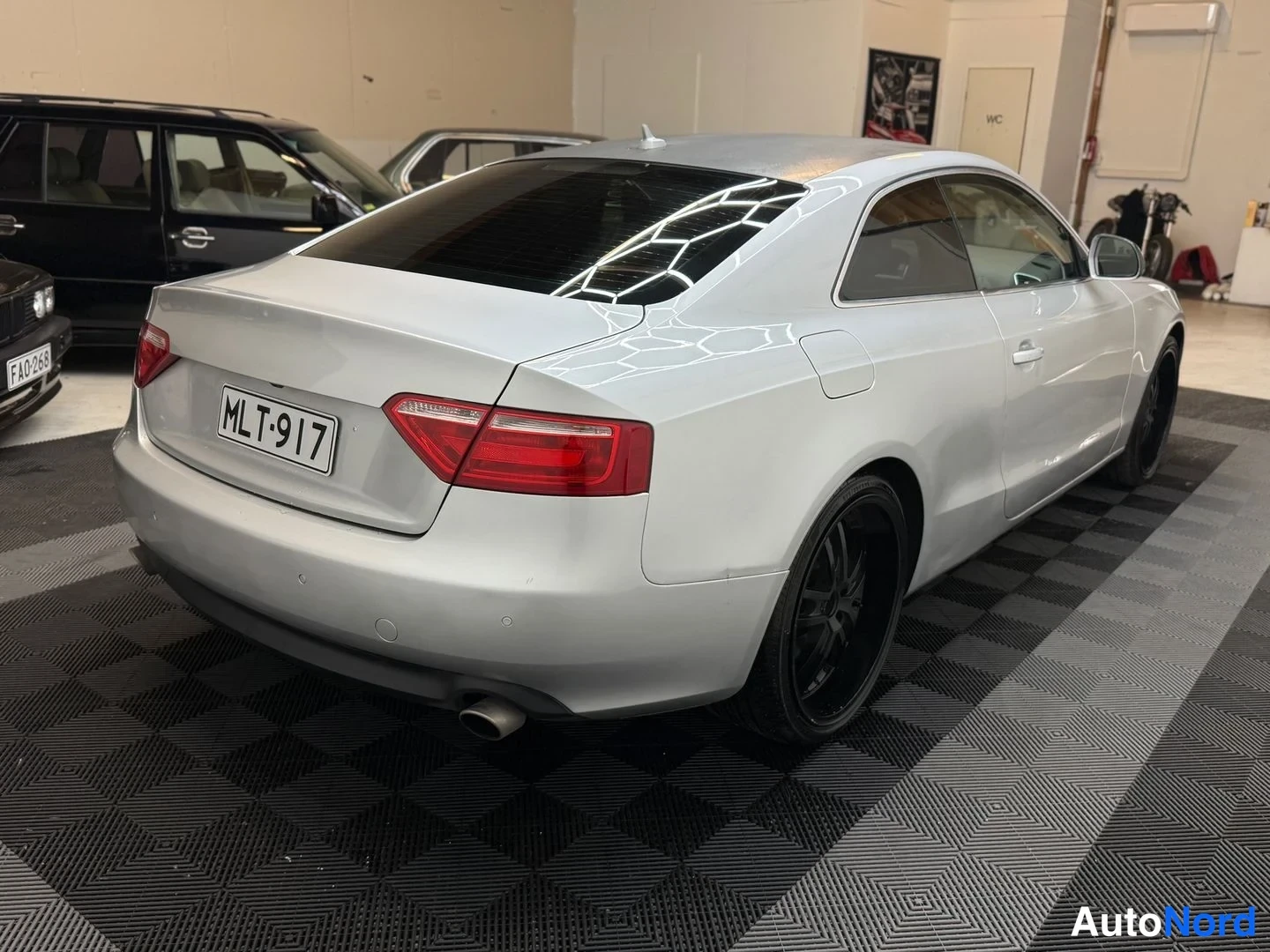 Takaviisto: Hopeanvärinen Audi A5 -coupe takaviistosta, rekisterikilpi ja mustat vanteet.