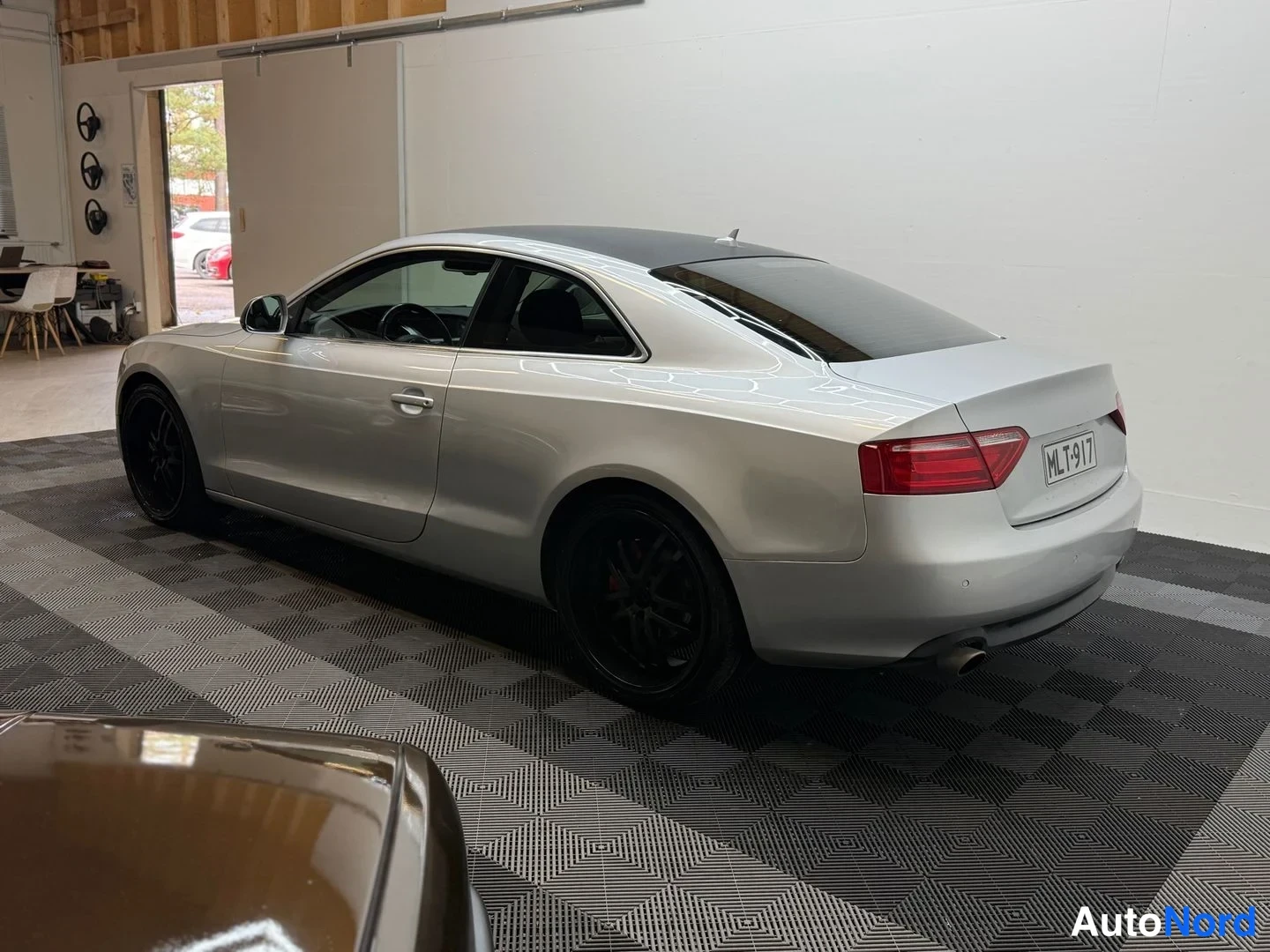 Takaviisto: Audi A5 -coupé sivulta takaviistosta, hopeanvärinen kori ja mustat vanteet, rekisterikilpi.