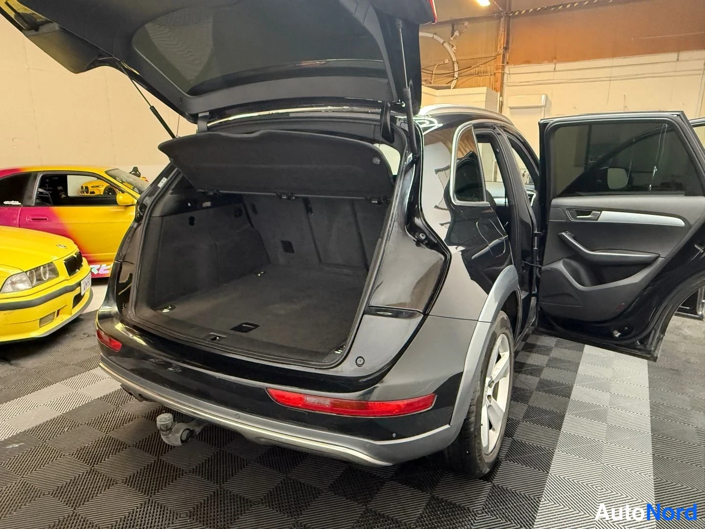 Takaviisto: Audi Q5:n takaosa ja sivu auki avatulla tavaratilalla ja takaovellalla, musta kori, perävaunun vetokoukku näkyy puskurin alla.
