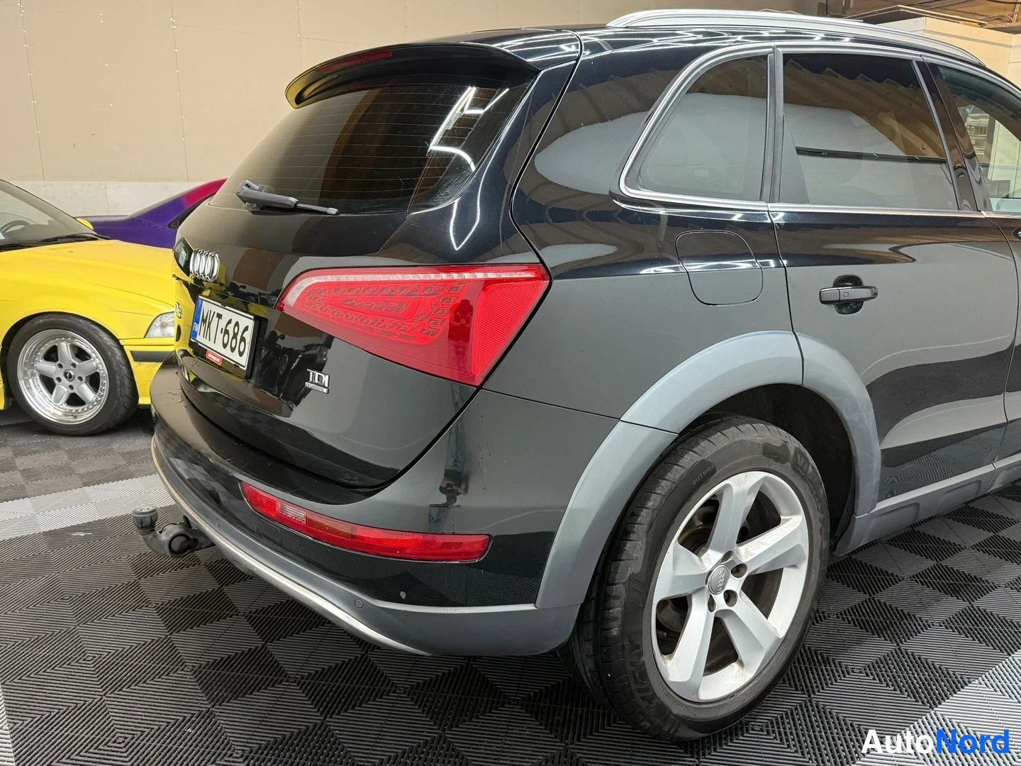 Takaviisto: Mustan Audi Q5:n takaosan ja sivuprofiilin kuva hallissa: takavalo, TDI-kyltti, rekisterikilpi ja pakokoukku.