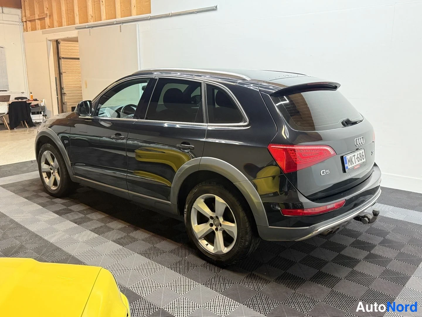 Takaviisto: Audi Q5, tumma pakettiauto kuvattu takaviistosta sisätilassa; perävaunukoukku näkyy takapuskurissa.