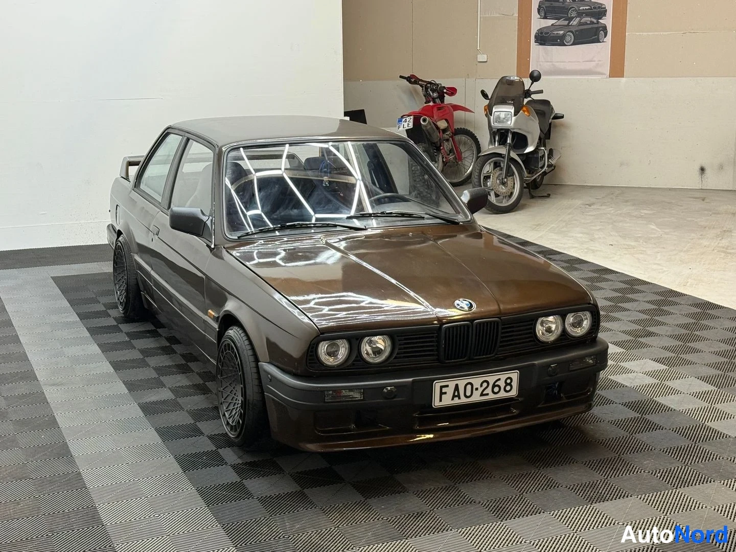 Etuviisto, nokka oikealle: Ruskean metallinhohtoinen BMW-coupé kolmannelta sektorilta kuvattuna hallissa; etusäleikkö ja pyöreät ajovalot näkyvät, rekisteritunnus FA0-268.