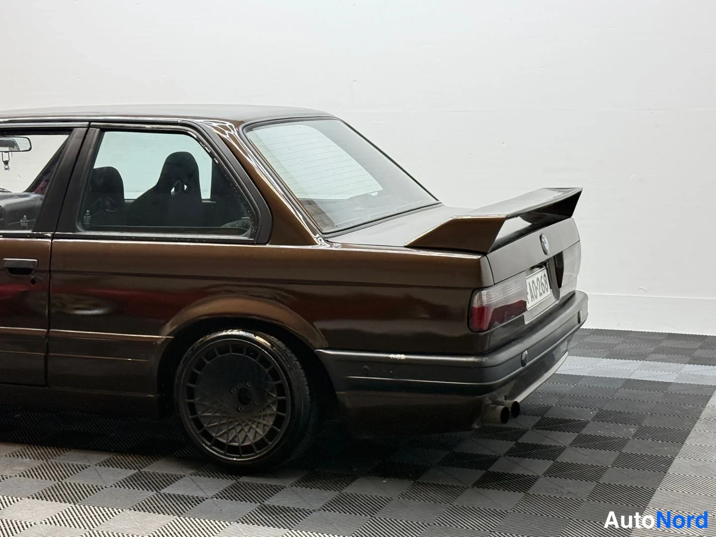 Takaviisto: Ruskean BMW E30 -sedanin takakolmasosa; koriin integroitu takasiipi, punaoranssit takavalot ja neljä pakoputkea. Rekisterikilpi AO-288.