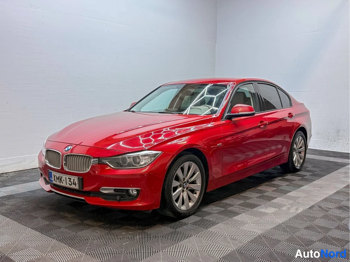 Etuviisto, nokka vasemmalle: Punainen BMW 3-sarjan sedan edestä vasemmalta kuvattuna, rekisteritunnus.