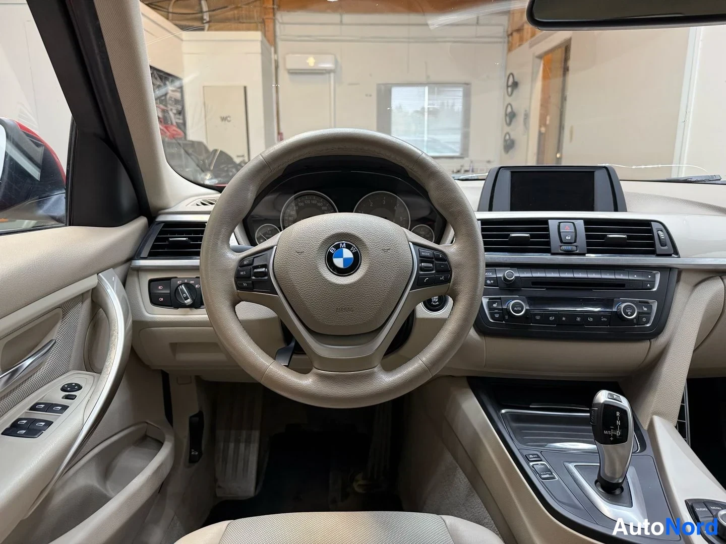 Edestä: Ohjauspyörä ja kojetahti kuvattuna suoraan edestä; rattiinmerkki BMW ja matkustamon hallintapaneelit näkyvät.