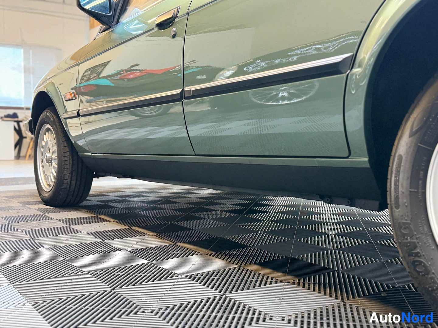 Sivulta: BMW 324d sivulta alakulmasta, vihreä ovi ja kylkisuoja, takapyörän vannes osin kuvassa.