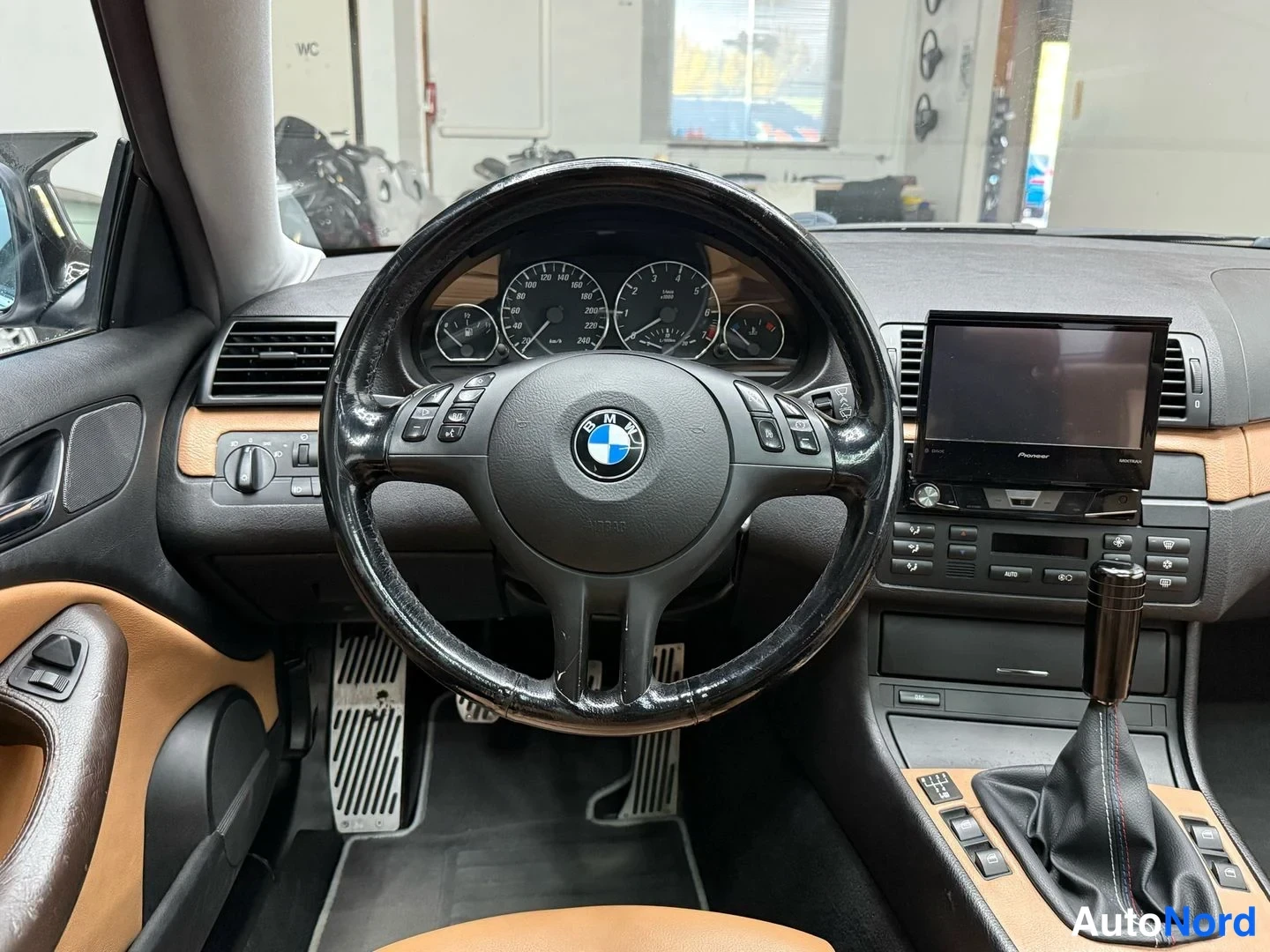 Edestä: BMW:n ohjauspyörä ja mitat lähikuvassa; osa mittareista ja Pioneer-näyttö näkyvissä.