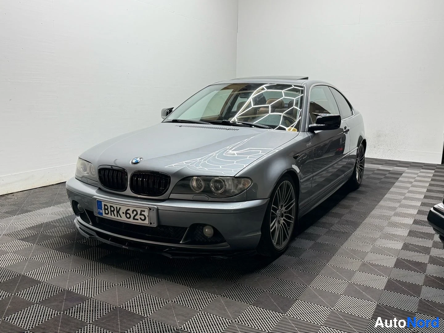 Etuviisto, nokka vasemmalle: Hopeanharmaa BMW Coupé kuvattu kulmasta edestä vasemmalla, rekisterikilpi, musta kiiltävä etusäleikkö, sade, monipaikkaiset vanteet ja avattava lasikat