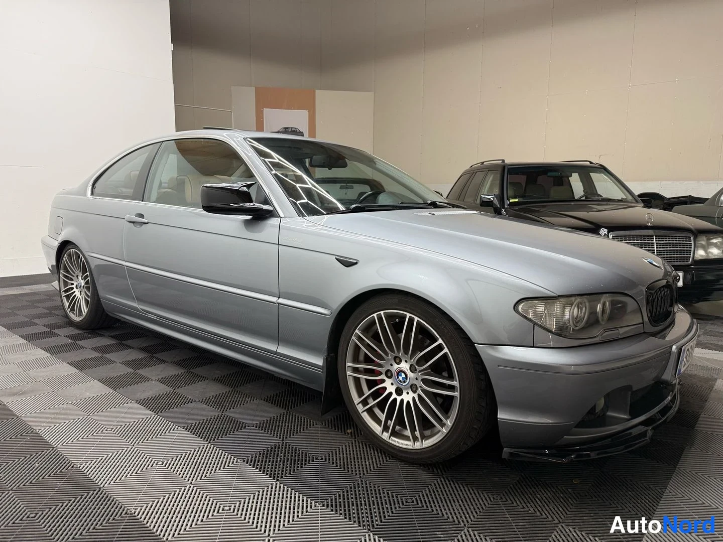 Etuviisto, nokka oikealle: BMW Coupé harmaassa autotallissa, etukulma oikealta, monipuoliset kevytmetallivanteet ja Bmw-merkki etukonepelti.