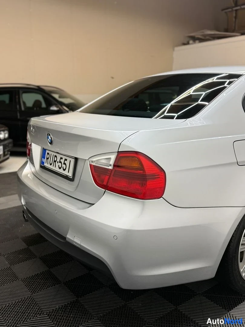 Takaa: Hopea BMW:n takapää suoraan takaa: takavalo, TÜV-kyltti ja takapuskurin sumuvalo.