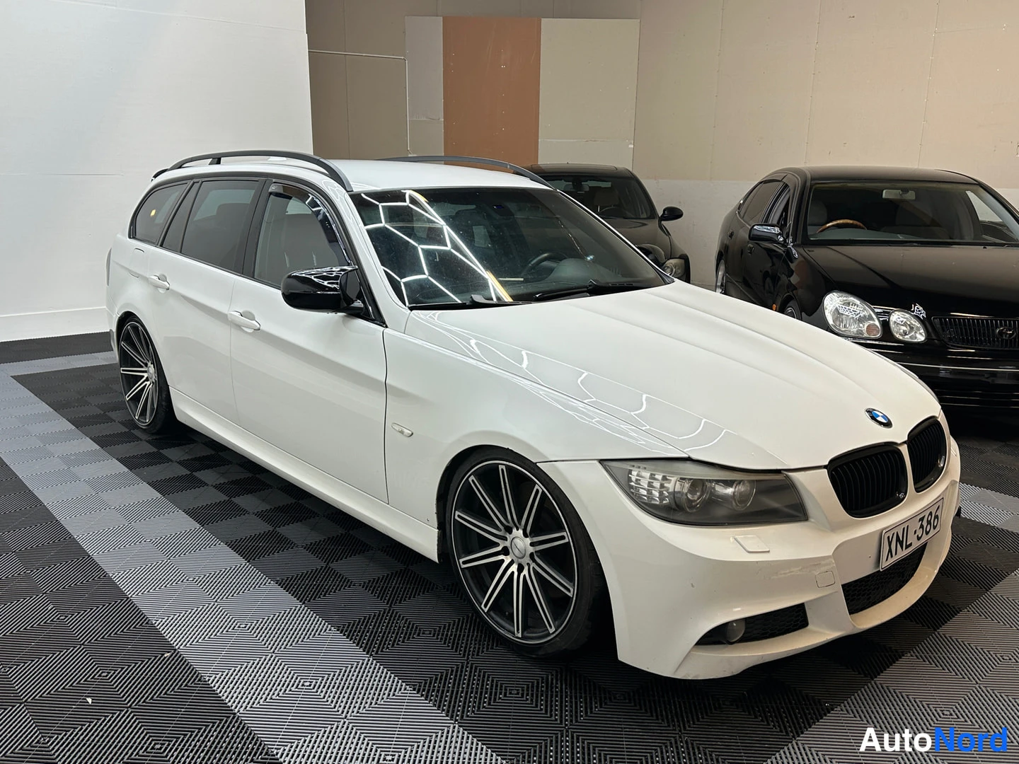 Etuviisto, nokka oikealle: Etukulmanäkymä valkoisesta BMW 3-sarjan farmarista, keulakoriste ja rekisterikilpi näkyvät.