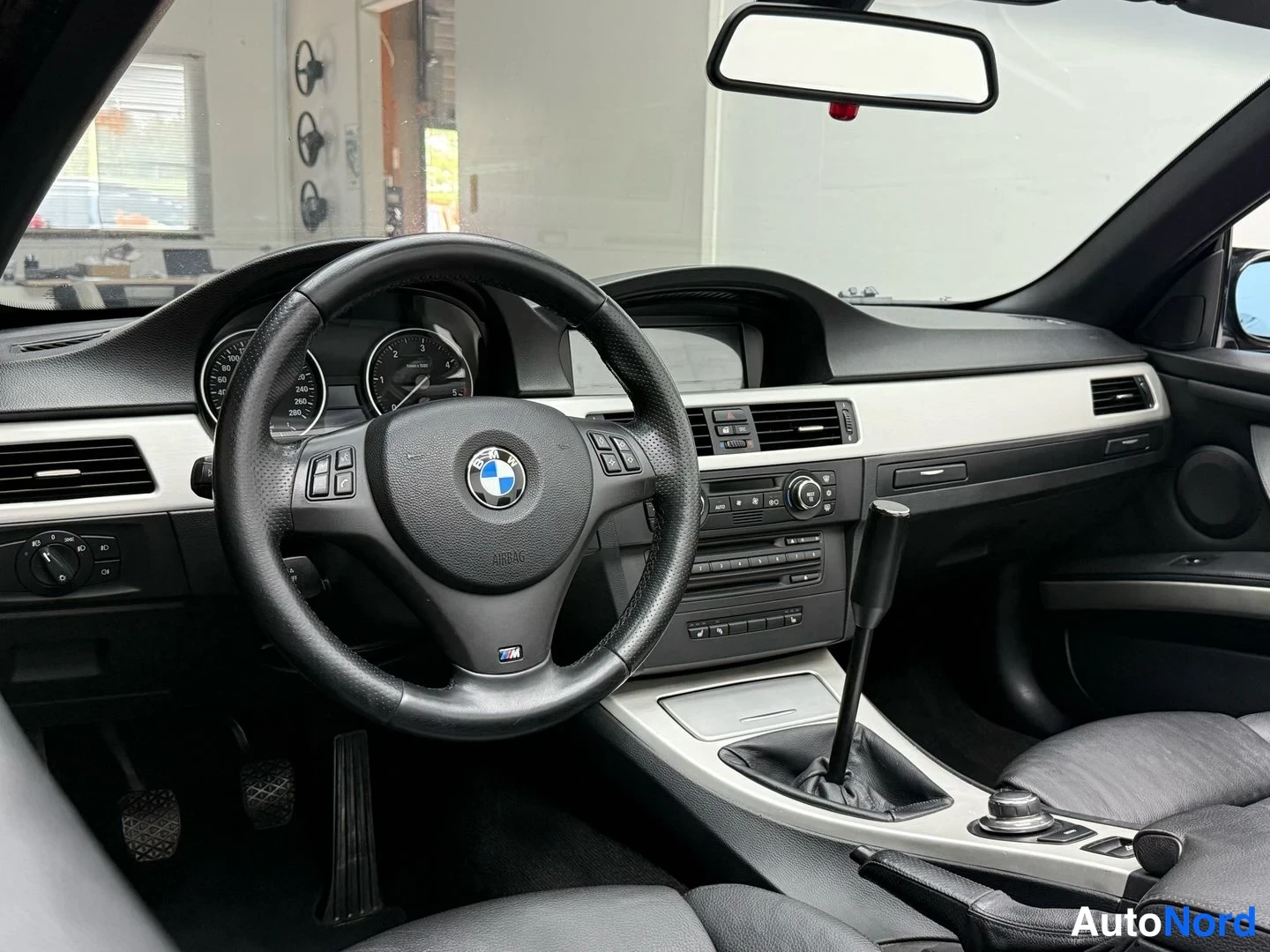 Sivulta: Kojelaudan ja ohjauspyörän näkymä: BMW-logollinen ohjauspyörä, M-merkintä ja manuaalivaihto SDS -ruuvi.