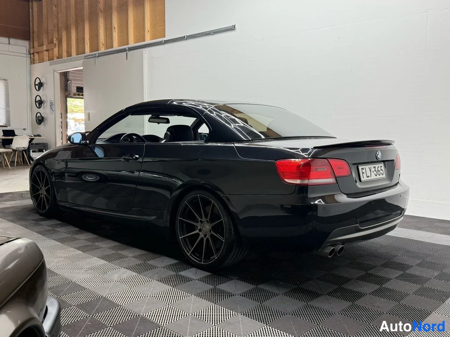 Takaviisto: Musta avokattoinen BMW-urheiluauto takakulmasta, suljettu kangaskatto, tuplapakoputki, mustat vanteet, rekisteritunnus.