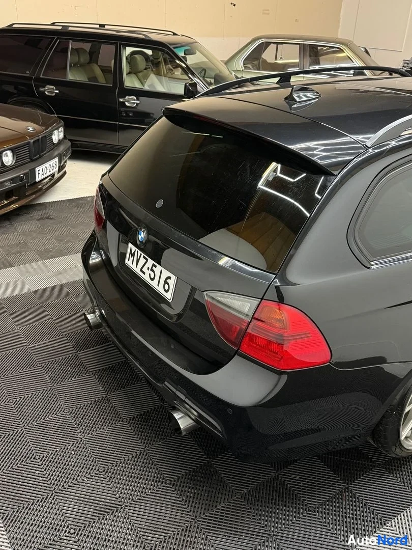 Takaviisto: Mustan farmariauto takakulma ylhäältä takaa, rekisteritunnus ja kattokaaret.
