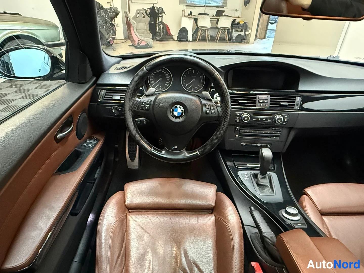 Muu: Kuljettajan näkökulma kojelautaan: BMW-ohjauspyörä, mittaristo, automaattivaihteiston valitsin ja iDrive-ohjain.