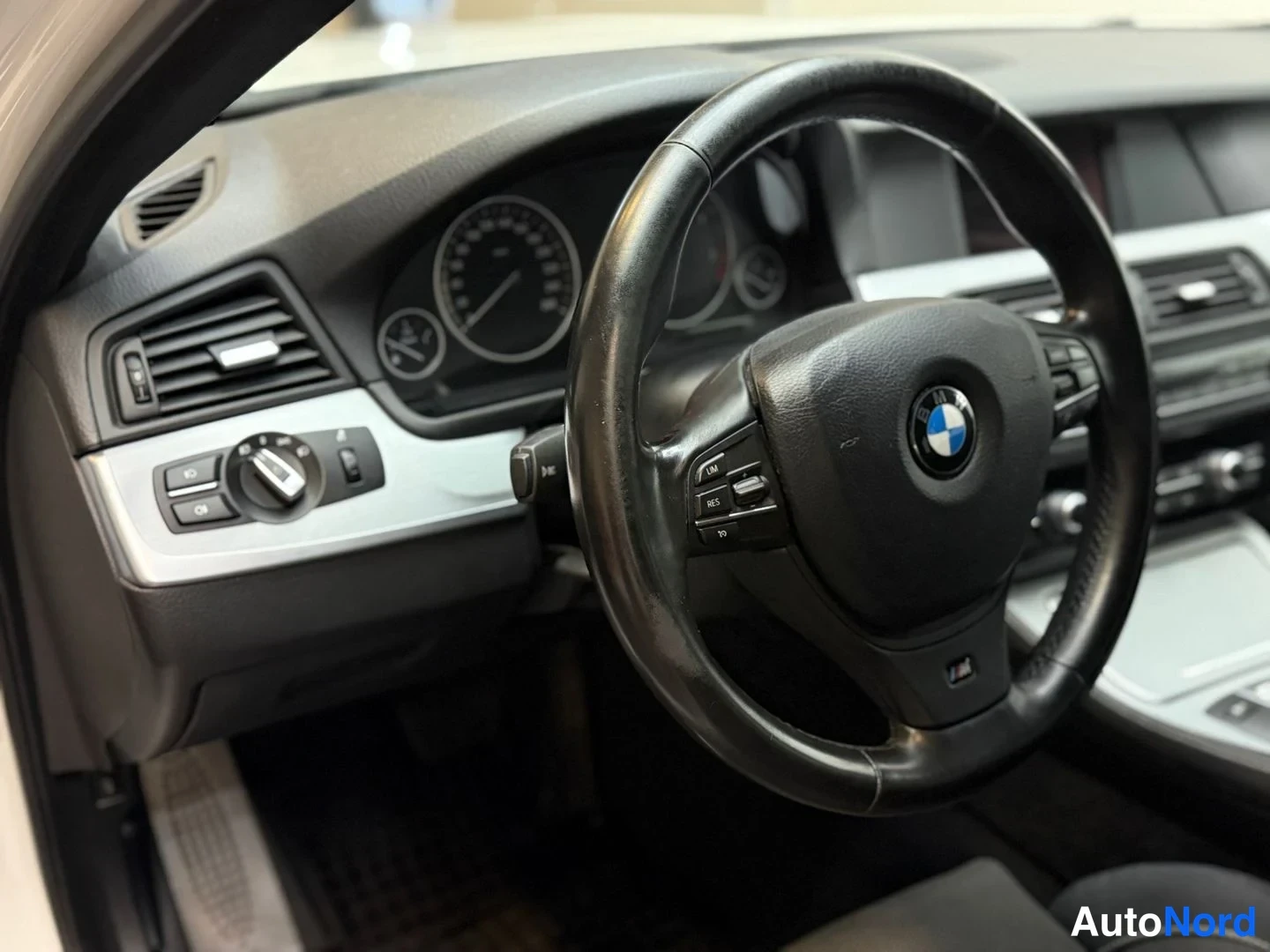 Edestä: Ohjaamo näyttää BMW-ohjauspyörän ja mittaristön lähikuvana.