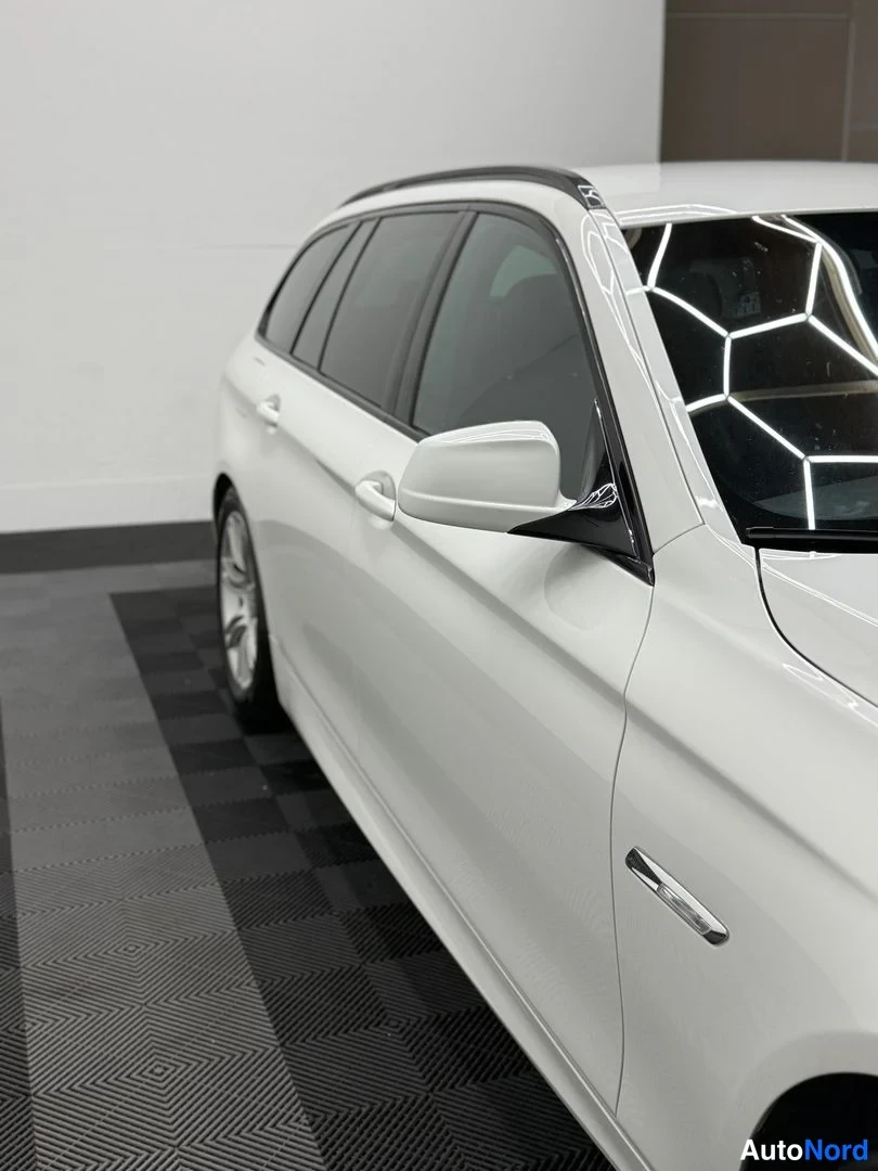 Sivulta: BMW 5 Touring -Auton sivuprofiili; kromilista, tummat ikkunat ja kattokaiteet näkyvät