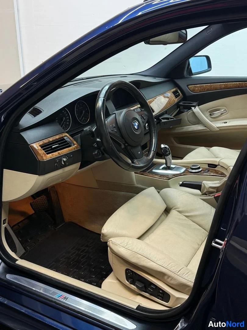 Muu: Kuljettajan puolen sisätilat: BMW-ohjauspyörä, puupaneloiden koristeet, automaattivaihteiston valitsin, iDrive-ohjain ja M-merkitty kynnyslista.
