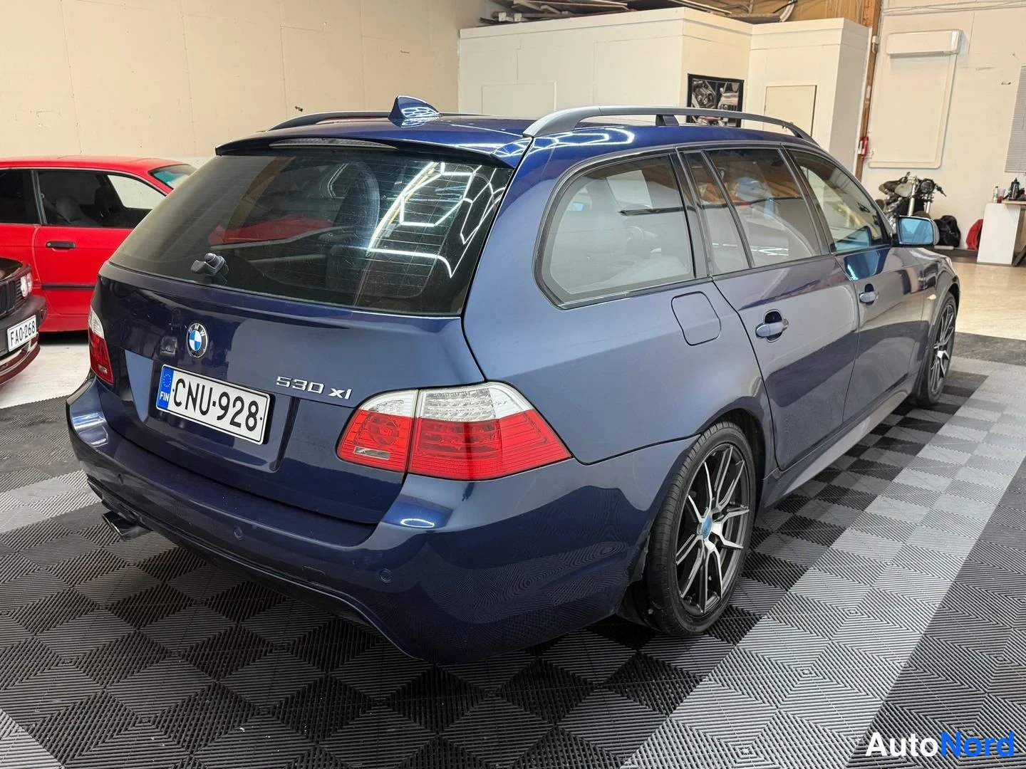 Takaviisto: Sininen farmariauto takaa sivulta kuvattuna, rekisteritunnus, kattokaiteet ja tummat kevytmetallivanteet.