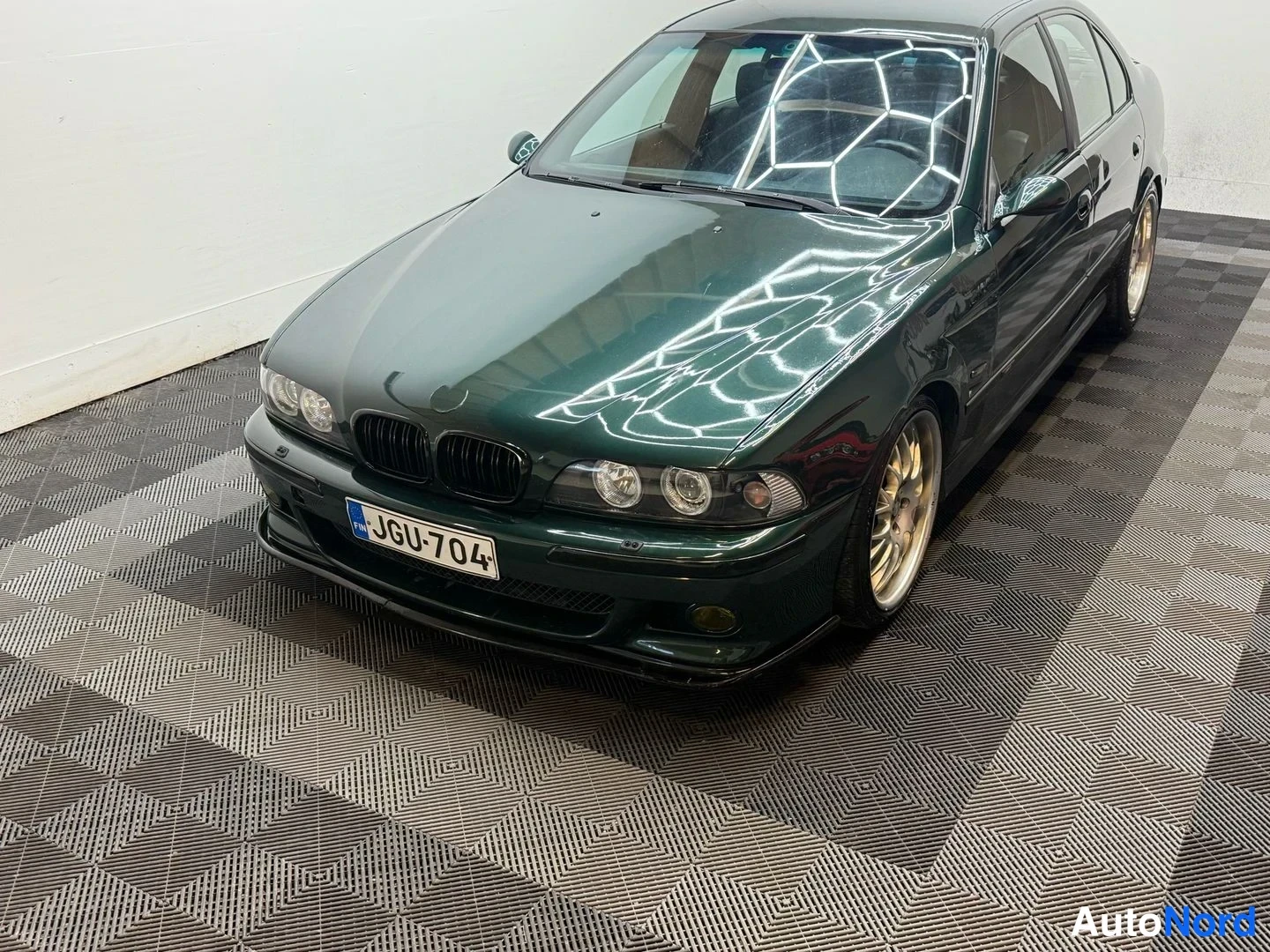 Etuviisto, nokka vasemmalle: Tummansinivihreä BMW-sedan etukulmasta vasemmalta, rekisteritunnus.