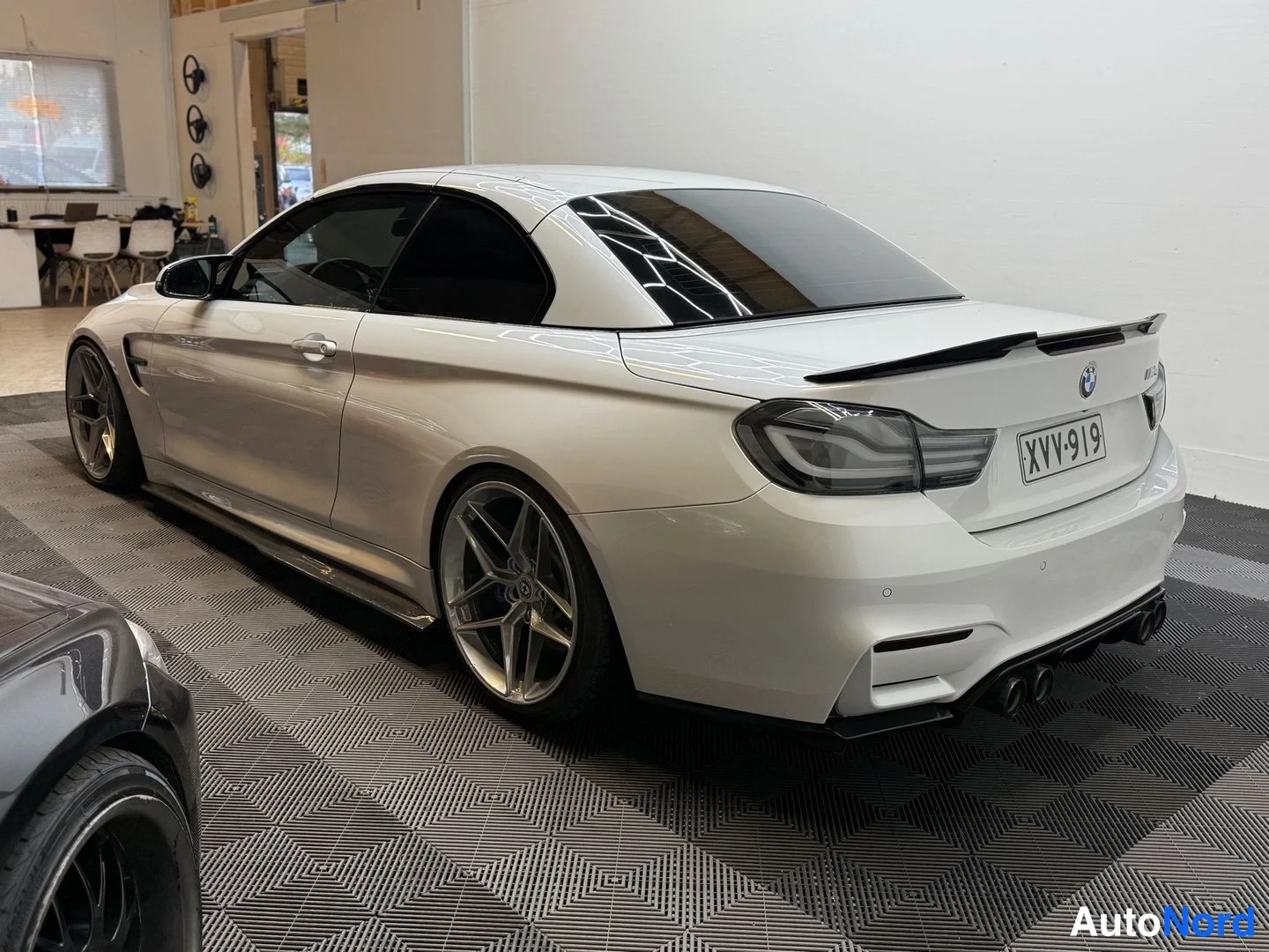 Takaviisto: Valkoisen BMW-cabrioletin takakulma varastohallissa, rekisterikilpi.