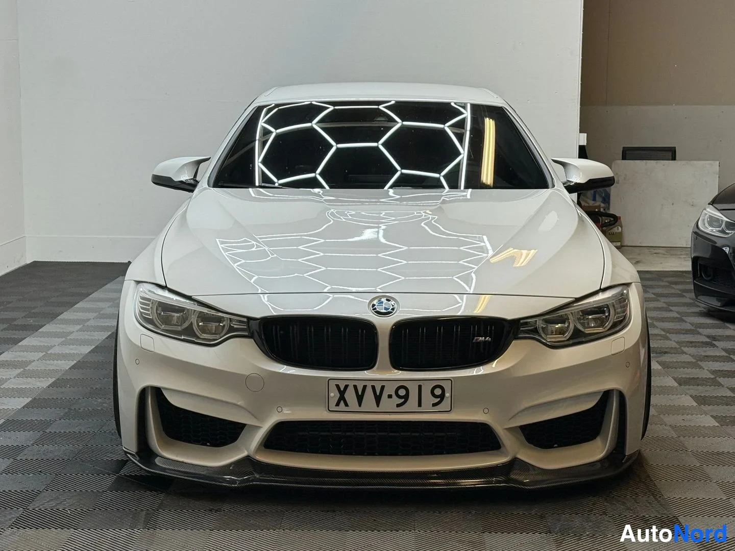 Edestä: Valkoisen BMW-auton suora etunäkymä, etusäleiköt ja -rekisteritunnus näkyvissä.