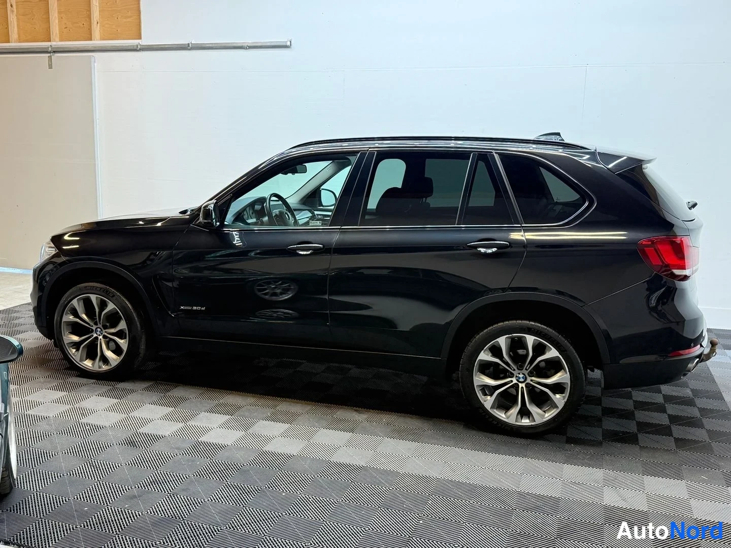 Takaviisto: BMW X5:n takaosan kolmasosasivukuva sisätilassa; musta koripaneeli, takavalo ja 18 tuuman kevytmetallivanne näkyvät.