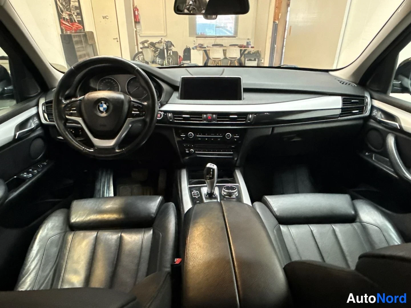 Edestä: BMW:n ohjaamo edestäpäin: BMW-ohjauspyörä, keskikonsoli ja edessä kaksi istuinta.
