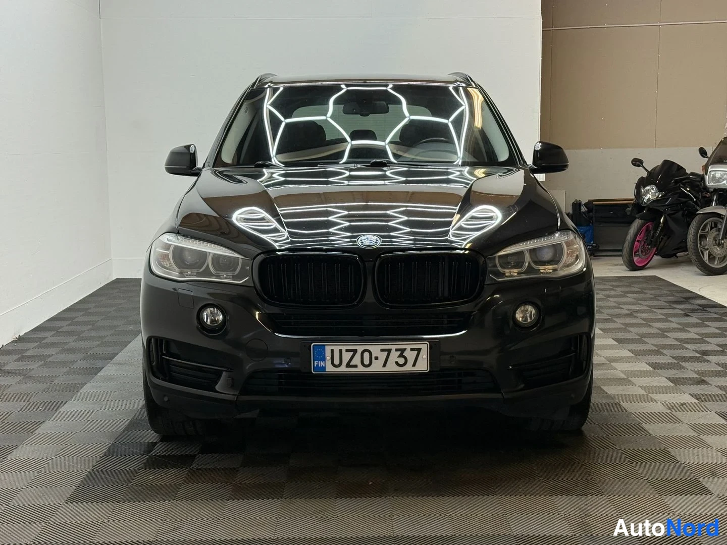 Edestä: Mustan BMW X5:n etunäkymä suoraan edestä, rekisteritunnus.