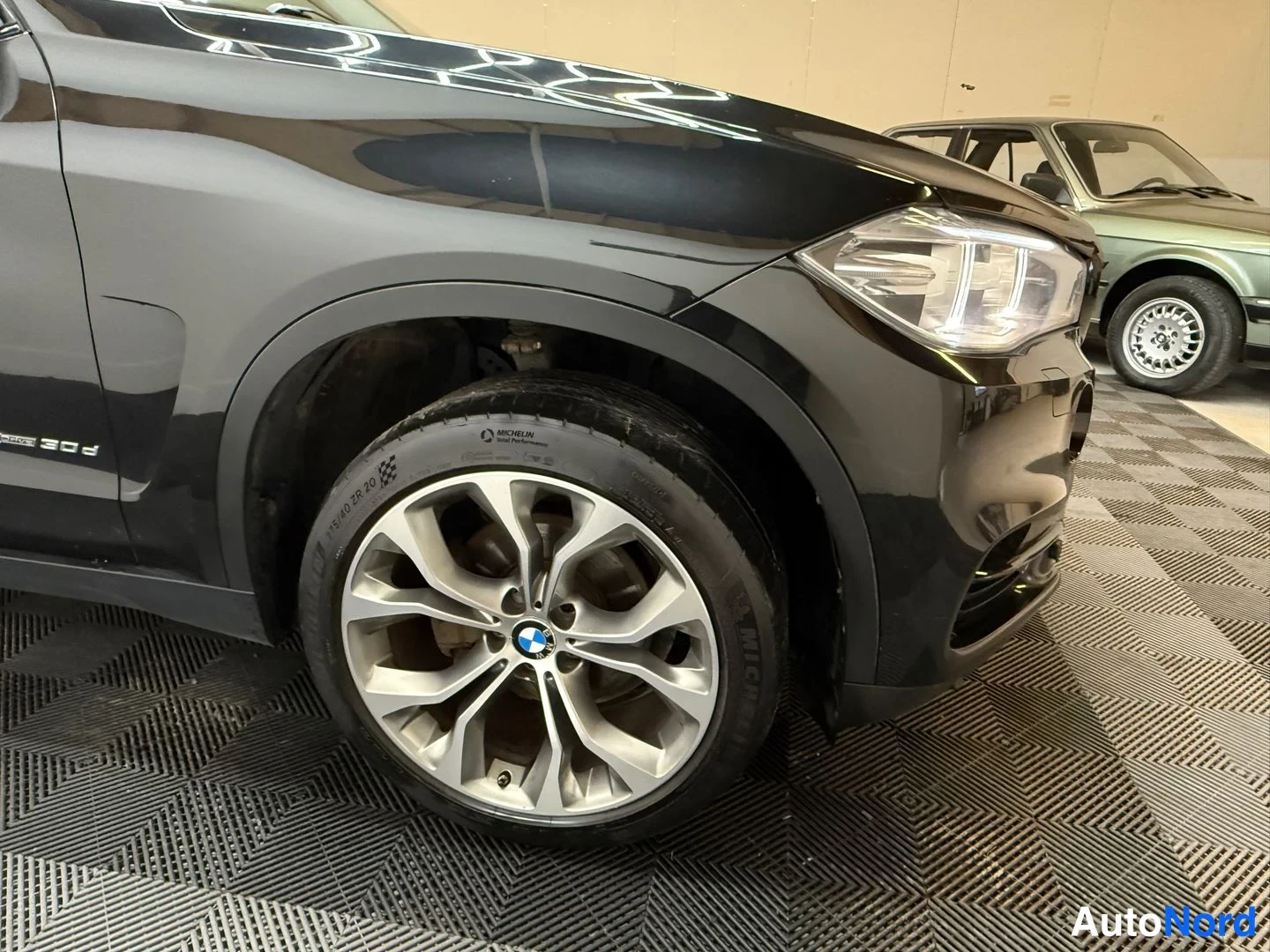 Etuviisto, nokka oikealle: BMW X5:n etupyörä ja etupelti lähikuvassa; vanteessa BMW-merkki, rengas Michelin.