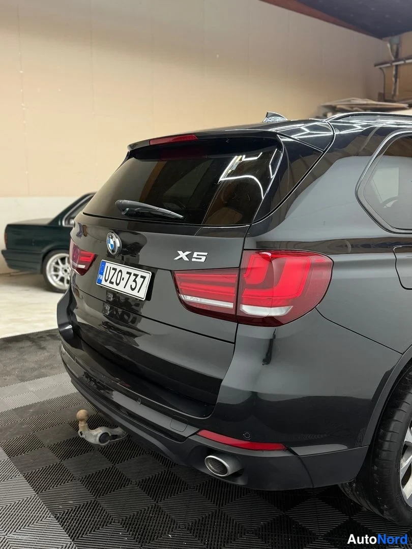 Takaa: BMW X5:n takaosa lähikuvassa; X5-merkki, rekisteritunnus ja takapuskurin vetoautohaken.