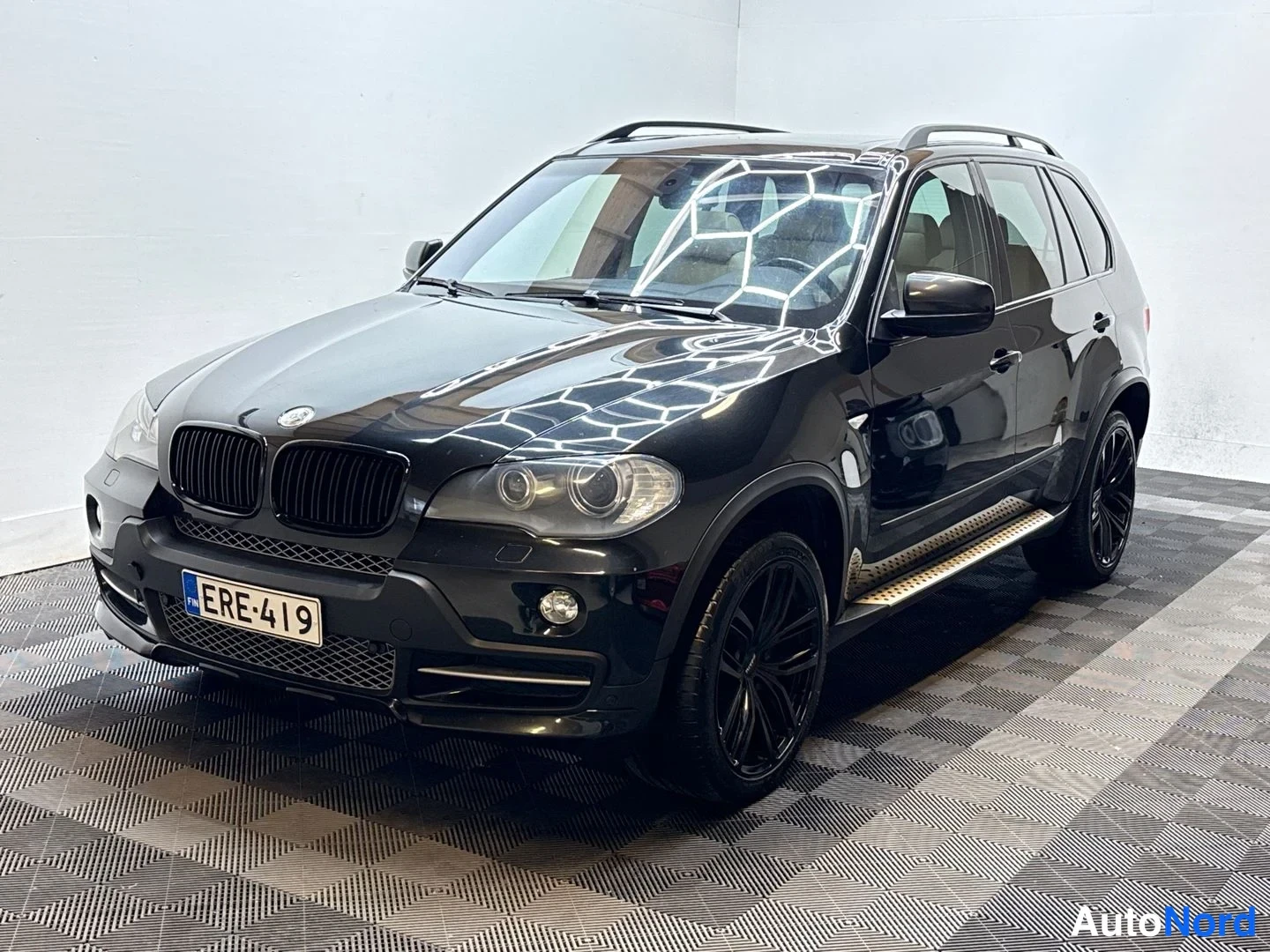 Etuviisto, nokka vasemmalle: BMW X5:n keulakolmasosa vasemmalta, musta maali, BMW-merkki ja rekisterikilpi näkyvissä.