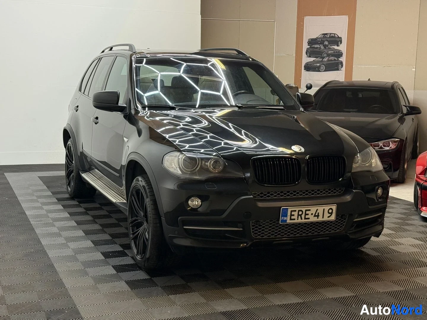 Etuviisto, nokka oikealle: Musta BMW X5 -maastauto etu kolmasosa vasemmalta, rekisteritunnus