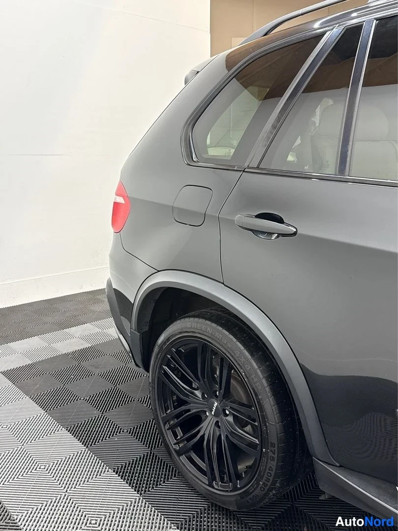 Sivulta: Lähikuva mustan SUV-auton takapyörästä ja takaovesta; musta kevytmetallivanne ja takavalon reunus erottuvat.