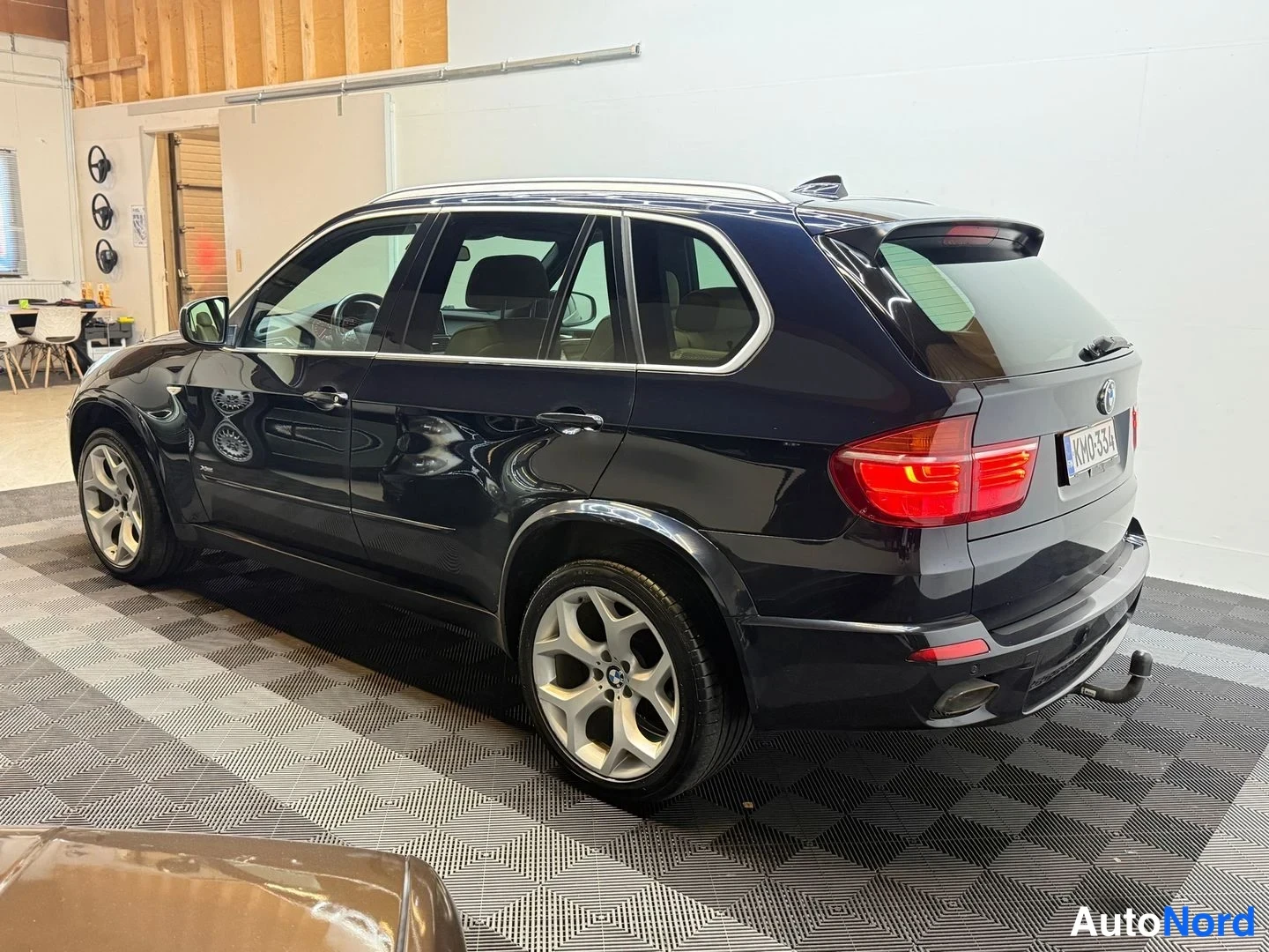 Takaviisto: BMW X5:n takaosa vasemmalta takaa kuvattuna tummansinisenä sisätiloissa