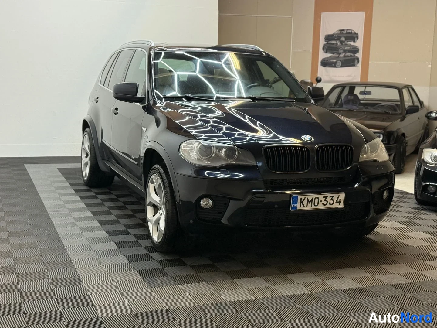 Etuviisto, nokka oikealle: Tumma BMW X5 -maast-auto sisätiloissa, etukulmakuva oikealta, rekisteritunnus KM0-334