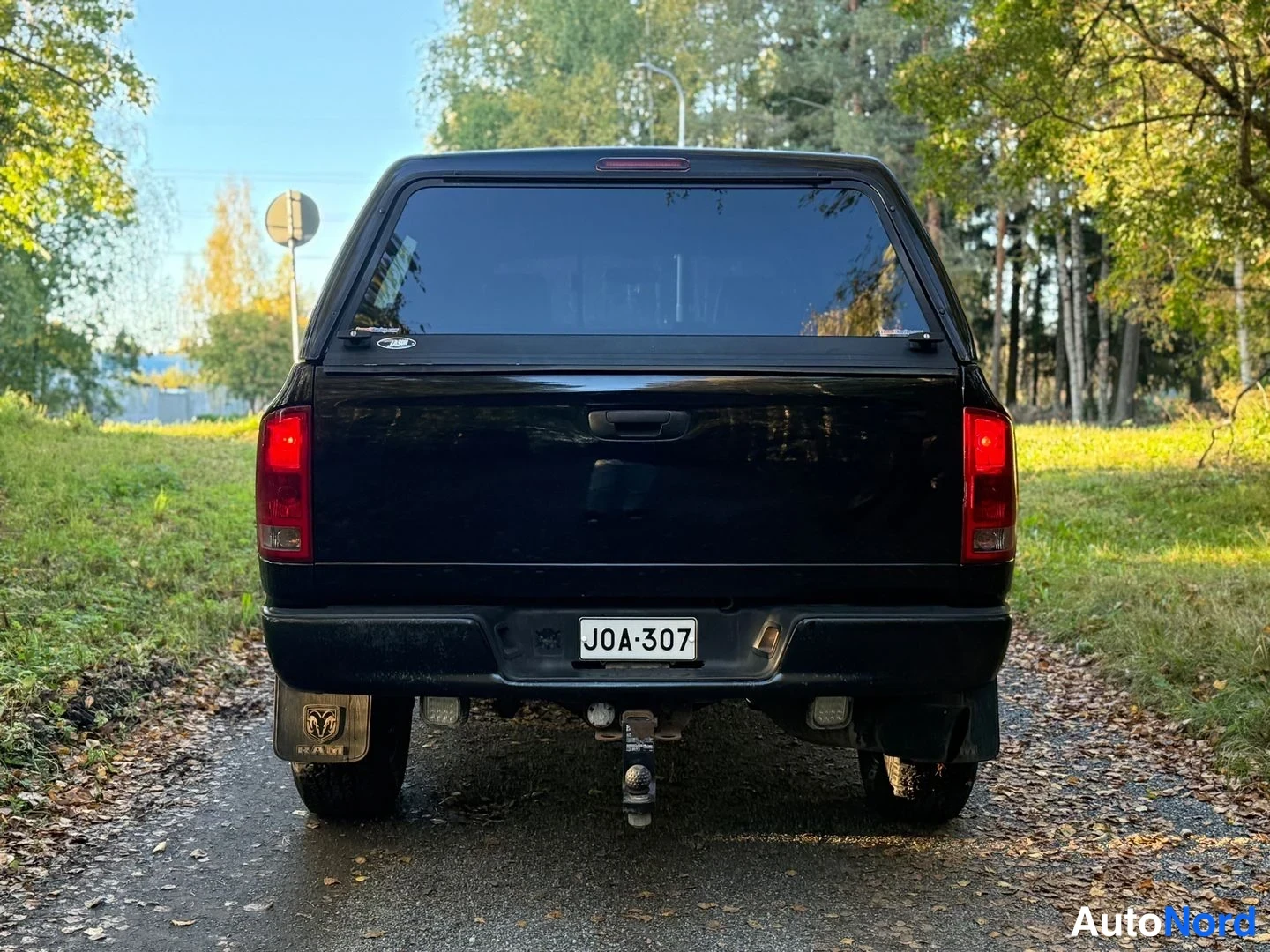 Takaa: Musta lava-automobiili takaa kuvattuna, rekisterikilpi ja vetokoukku näkyvissä.