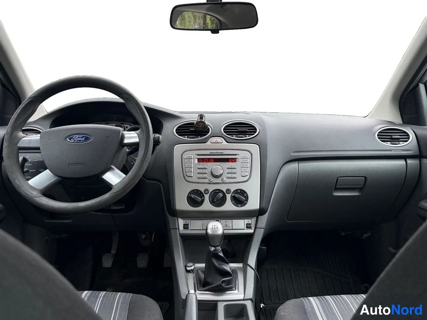 Muu: Ford Focusin kojelauta suoraan edestä: Ford-merkitty ohjauspyörä, radio- ja ilmastointisäätimet sekä manuaalivaihteen valitsin.
