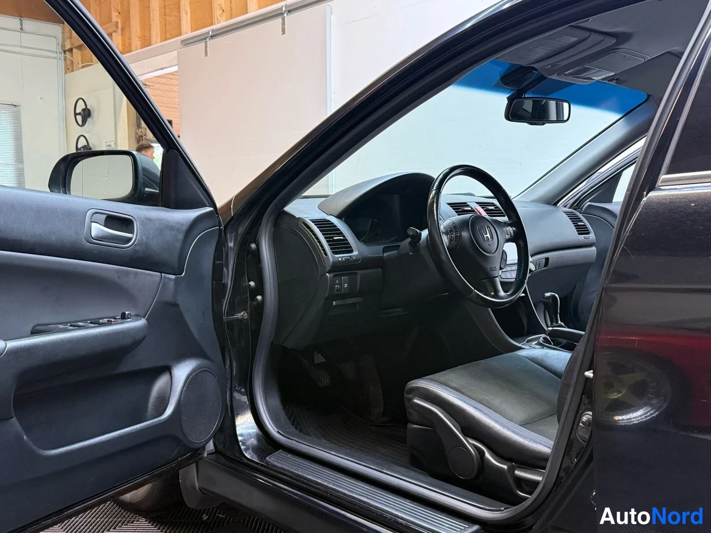 Muu: Auton etuistuin ja ohjaamo vasemmasta ovesta kuvattuna: Honda-merkillinen ohjauspyörä, käsivaihteisto, ovessa ikkunakytkimet ja äänentoistokaiutin.