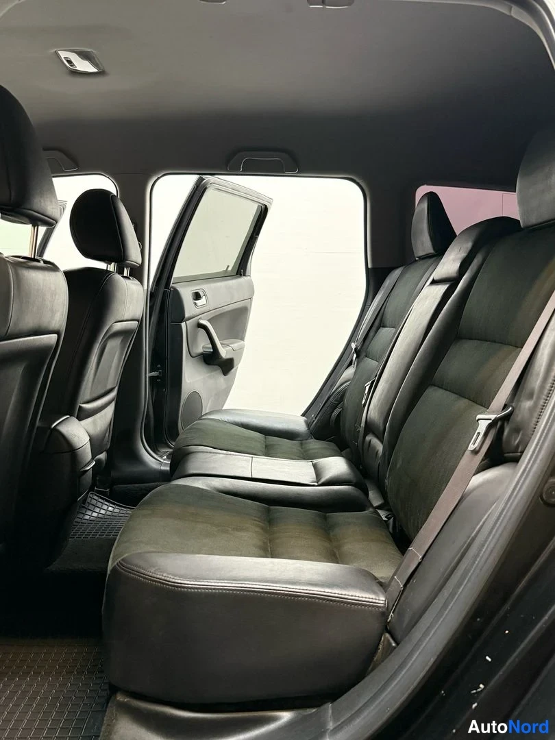 Muu: Takapenkki oikealta takaovesta kuvattuna: tumma taittuva istuin, turvavyö ja takaoven kahva näkyvissä.