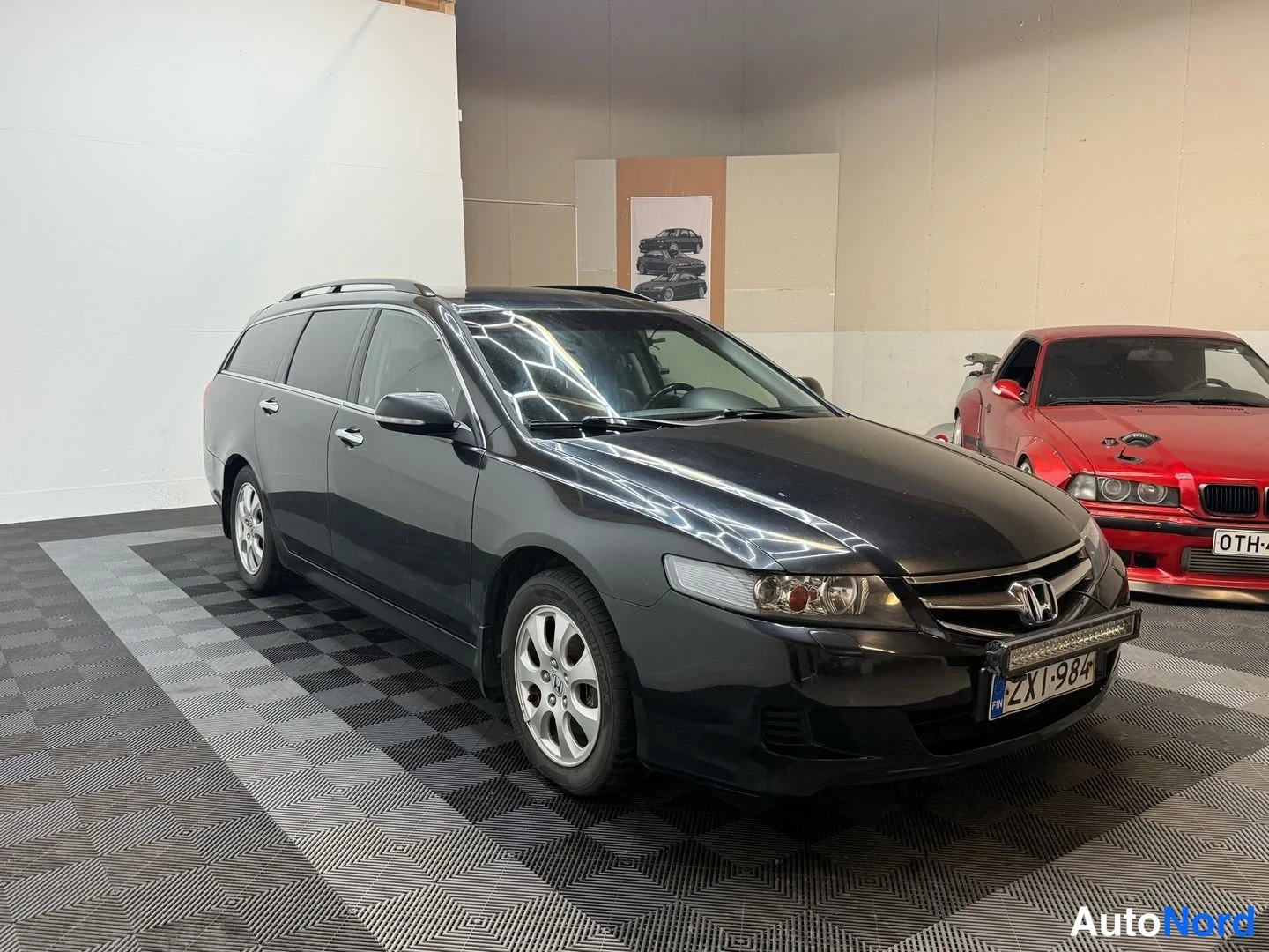 Etuviisto, nokka oikealle: Musta Honda Accord Tourer -farmari kuvattu kolmeneljännesnäkymässä etuosasta oikealta näkyen, kattoon asennetut kiskot ja etupuskkerissa lisävalobari.