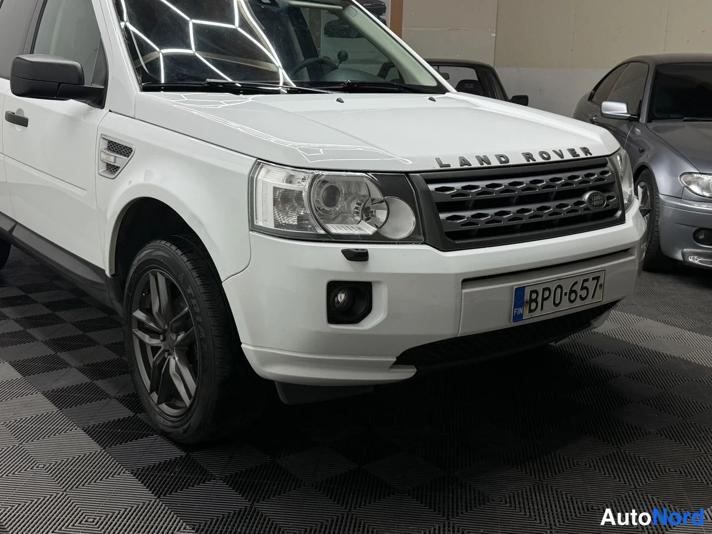 Etuviisto, nokka oikealle: Valkoinen Land Rover Freelander 2 etukulmasta, rekisterikilpi BP0-657, Land Rover -teksti konepellin etureunassa.