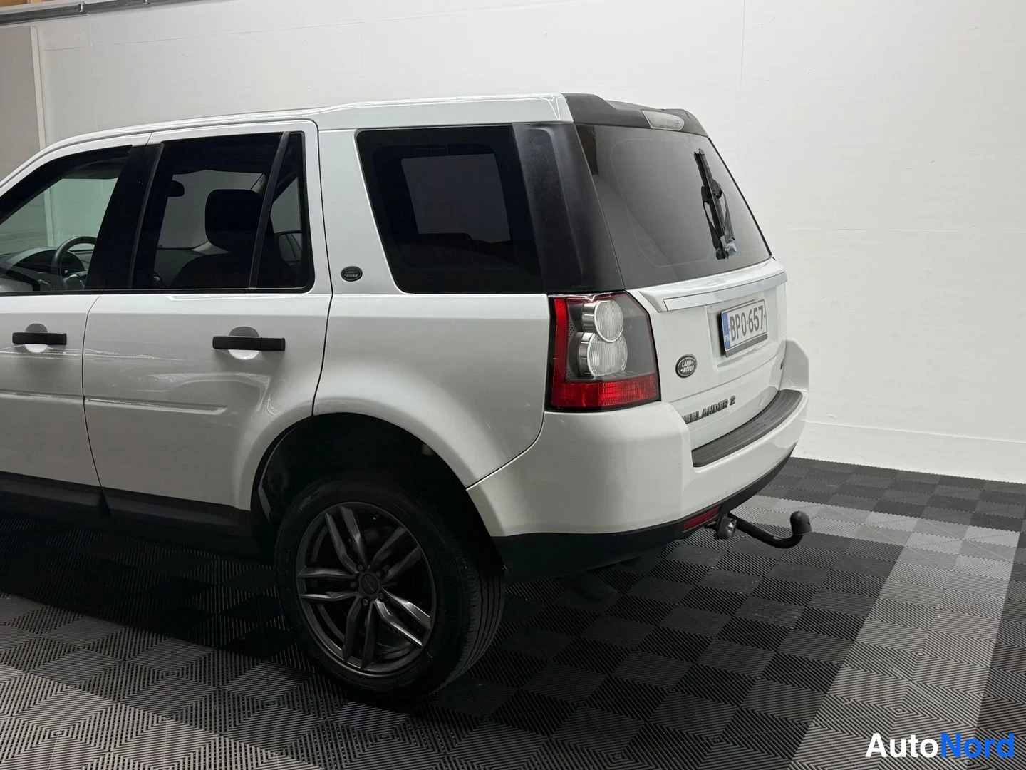 Takaviisto: Valkoisen Freelander 2:n takaosa ja kylki; takaova auki ja vetoarkin kiinnike näkyvissä.