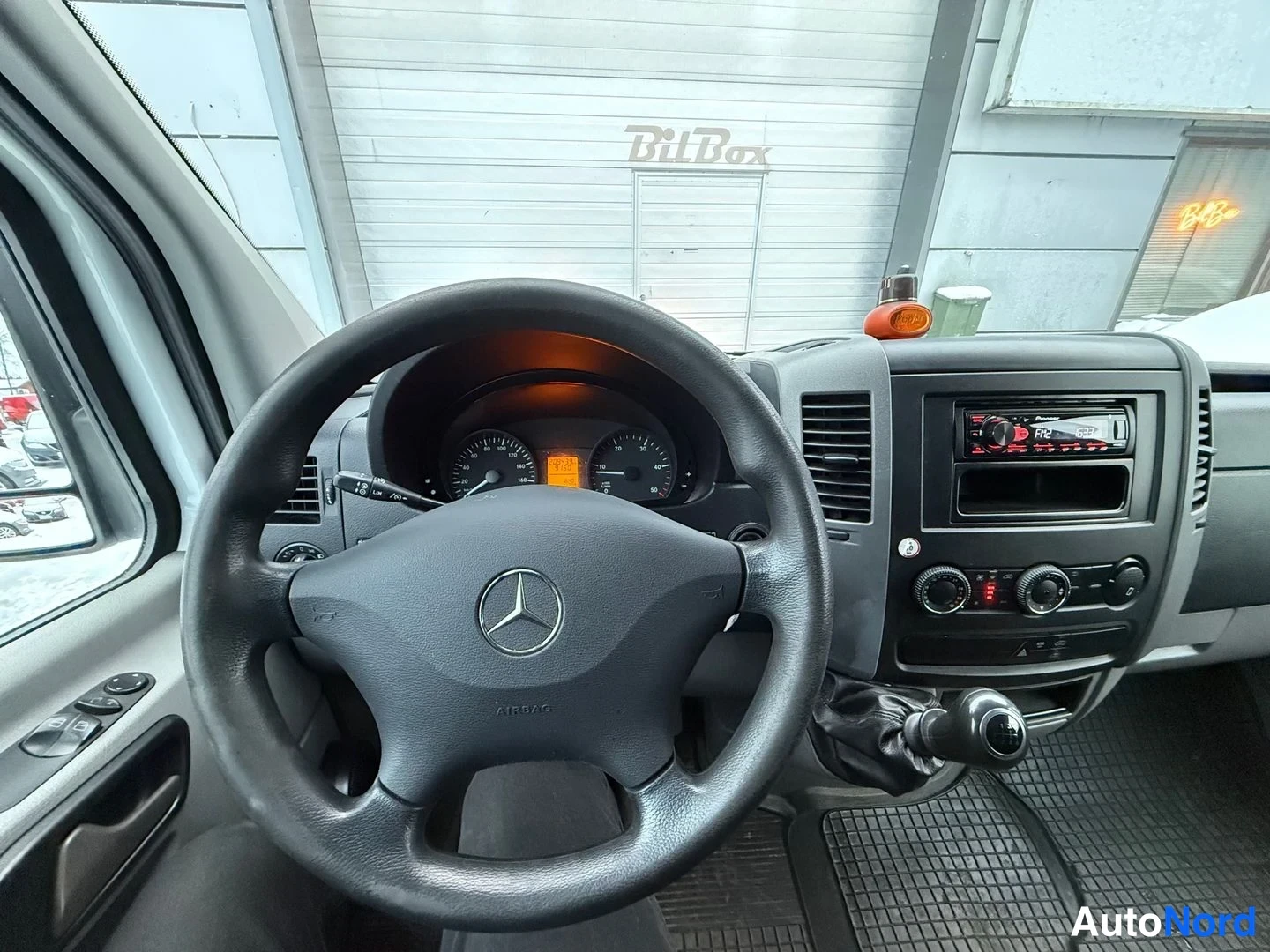 Muu: Ohjaamo näkyvänä ohjauspyörästä: Mercedes-tunnuksen merkki ja AIRBAAD-teksti ohjauspyörässä, analogiset mittarit, radio ja manuaalivaihtoheitin.